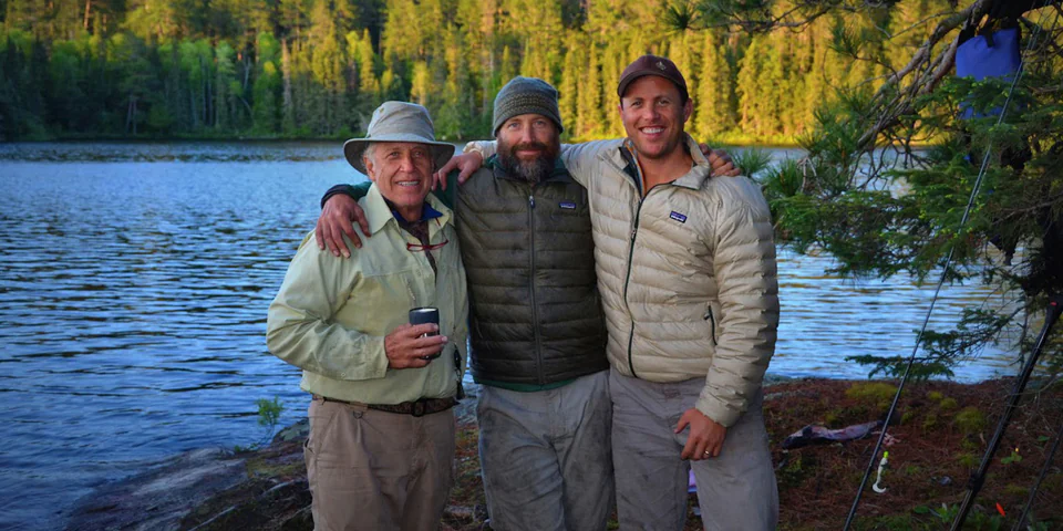 Three men standing with arms placed over each other's shoulders