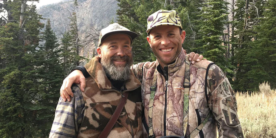 Two men standing with arms placed over each other's shoulders